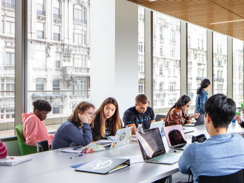 several students around a large conference table with large windows on one side